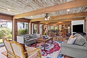 A spacious living area with a large sofa, a dining table, and a television.