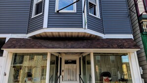 A corner house with a bay window, a front porch, and a visible storefront.
