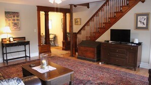 A living room with a wooden staircase, a television, a fireplace, and a coffee table with a candle.
