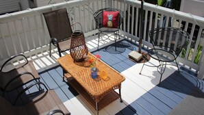 A deck with wicker furniture, a table, and chairs.