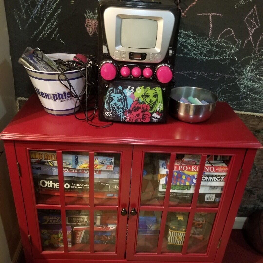 A red cabinet with glass doors containing various items.
