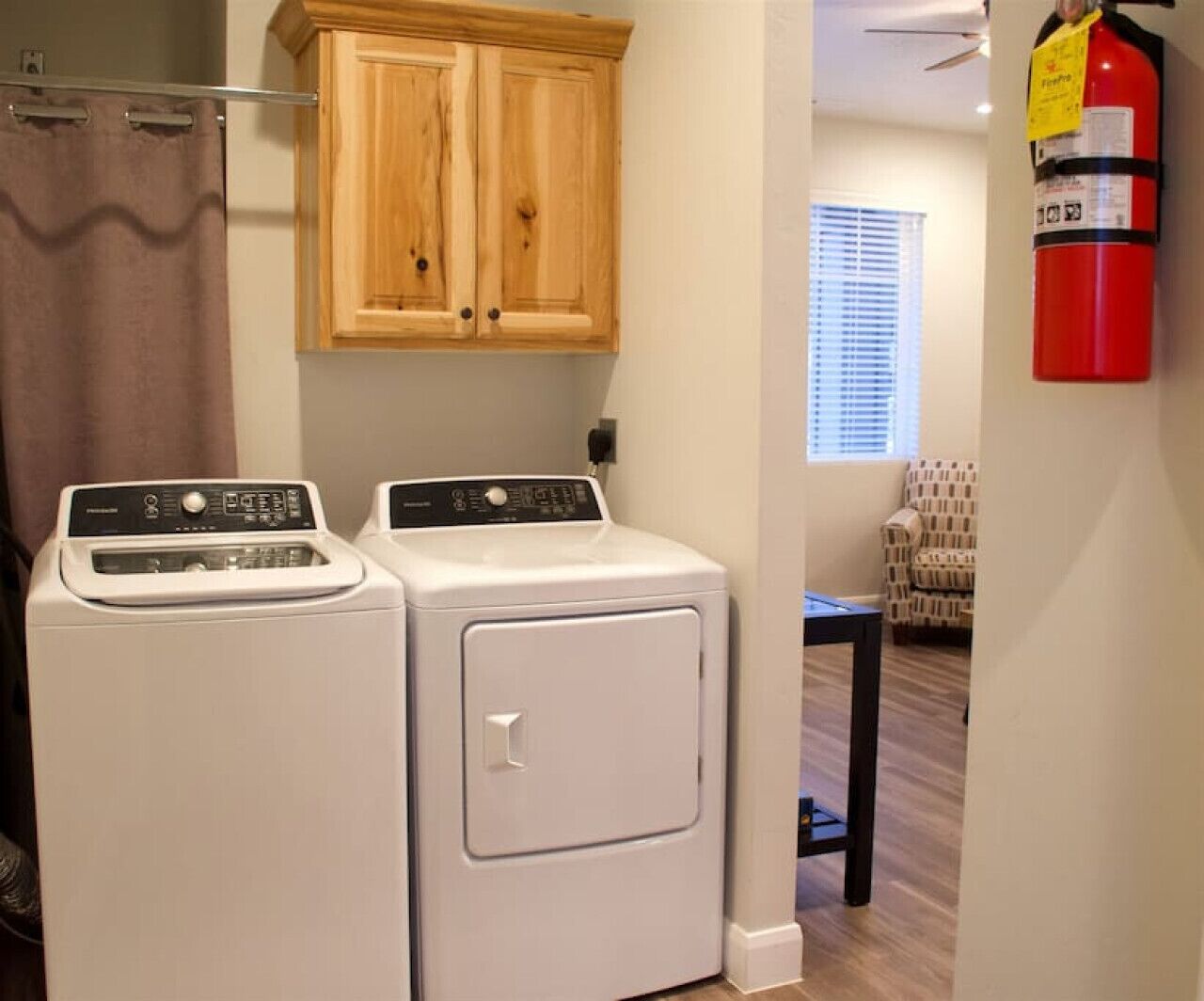 A laundry area with two front-loading washers and a wooden cabinet above.
