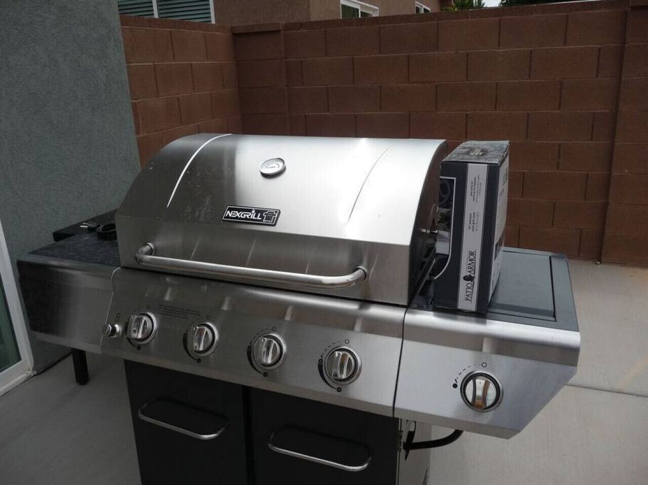 Un barbecue d’extérieur en acier inoxydable, doté de quatre brûleurs et d’un brûleur latéral, d’un thermomètre intégré et d’un écran numérique.