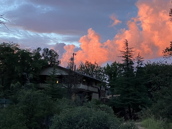 A two-story building surrounded by dense forest, with a prominent cloud formation in the sky. - SPECIAL OFFER! Relaxing Secluded Payson Home with Scenic View! (Payson)