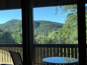 Enjoy the serene forest view from your balcony with a table and chairs.