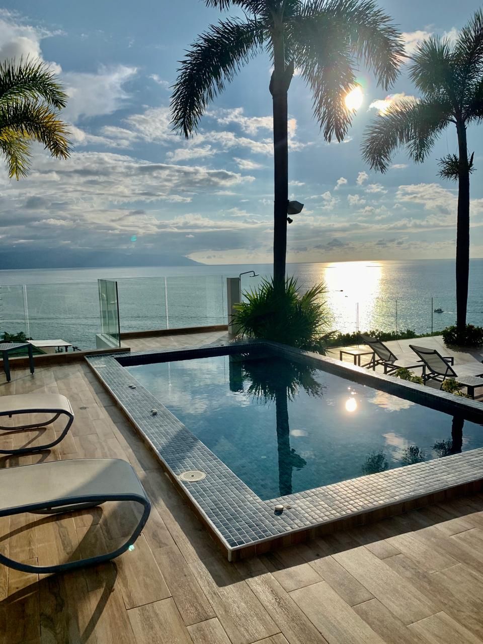 An infinity pool with a clear view of the ocean and a sunset.