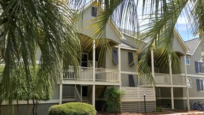 A multi-story building with balconies, a paved walkway, and surrounding greenery. - Tranquil tidal marsh setting (Seabrook Island)