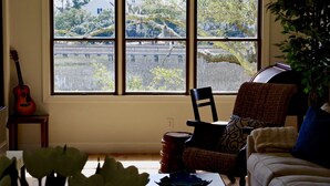 A room with a large window, a guitar, a chair, and a couch. - Tranquil tidal marsh setting (Seabrook Island)