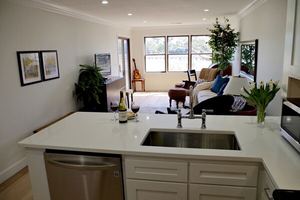 A modern kitchen with a central island, a built-in dishwasher, and a large window offering a view of the outdoors.