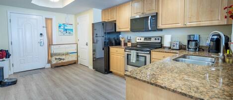Una cocina con armarios de madera, un refrigerador de acero inoxidable, un microondas, una estufa y un lavaplatos.