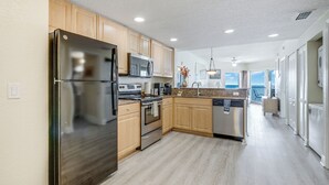 A modern kitchen with wooden cabinets, stainless steel appliances, and a light wood floor.