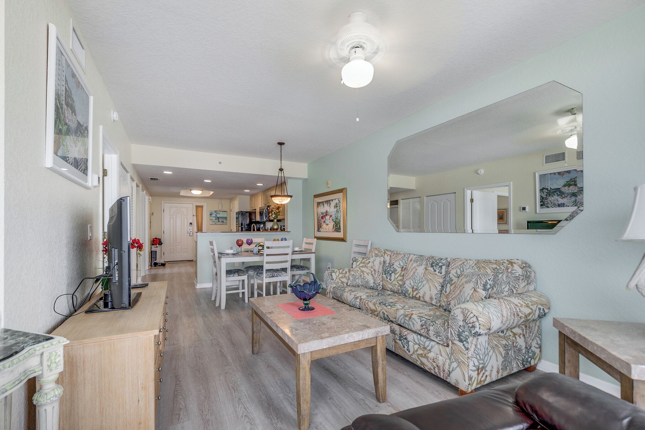 A living room with a sofa, a coffee table, a TV, and a dining area with chairs and a table.