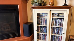 A living room with a fireplace, a bookshelf filled with DVDs, and a decorative vase on the mantel. - 1A8 Views, Shared Pool & Hot Tub, Private Patio & Garage (Moab)