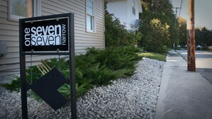 Señal del hotel 'The Seven Sevens', con un sendero de grava y follaje.