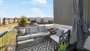 A balcony with a sofa, a patterned rug, and a view of neighboring buildings. - Townhome with Loft & Contemporary Flair!  Convenient & Straight Route to A&M! (College Station)