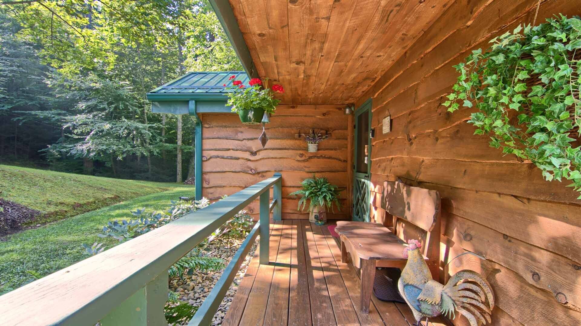 A wooden cabin with a porch, a bench, a table, and a rooster.