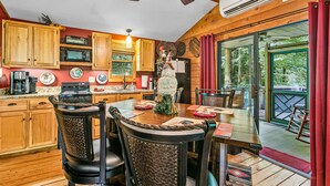 Une cuisine avec des meubles de rangement en bois, une cuisinière et un coin repas comprenant des chaises et une table.