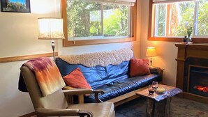 Ein gemütliches Wohnzimmer mit einer Ledersofa, einem Holzstuhl, einem kleinen Tisch mit Getränken und einem Kamin.