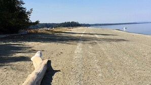Ein Kiesstrand mit einem Holzpfahl und einem Boot in der Ferne.