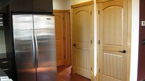 Una cocina con un refrigerador de acero inoxidable, armarios de madera y una puerta de madera.