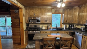 A cabin-style kitchen with wooden cabinets, a stainless steel stove, a microwave, and a coffee maker. - 4 bedroom, Secluded 13 Acres on Bennetts Branch of the Sinnemahoning Creek.  (Benezette)