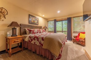 Une chambre à coucher avec un grand lit, une table de chevet en bois, une carte accrochée au mur et une fenêtre avec des rideaux.