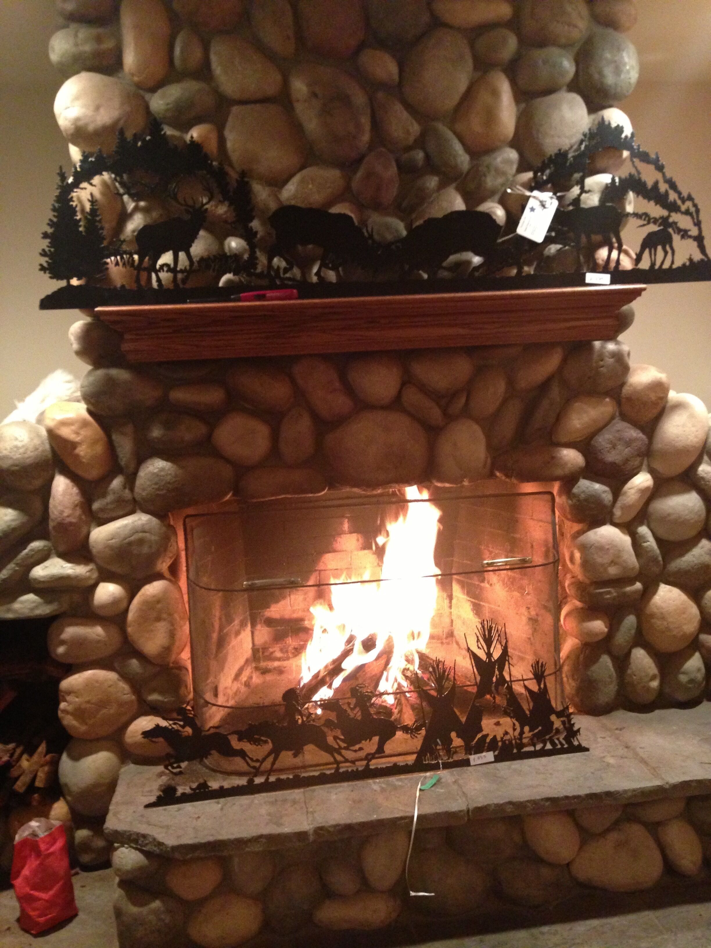 A stone fireplace with a fire burning inside, surrounded by decorative elements and a shelf above.