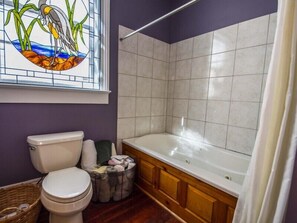 Une salle de bain équipée de toilettes, d’une baignoire et d’un vitrail.