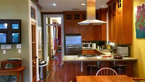 Una cocina con armarios de madera, un refrigerador de acero inoxidable, un microondas y un lavamanos.