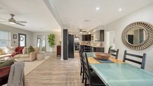 Uma sala moderna com sofá, mesa de centro e um espaço de jantar com mesa de vidro e cadeiras.
