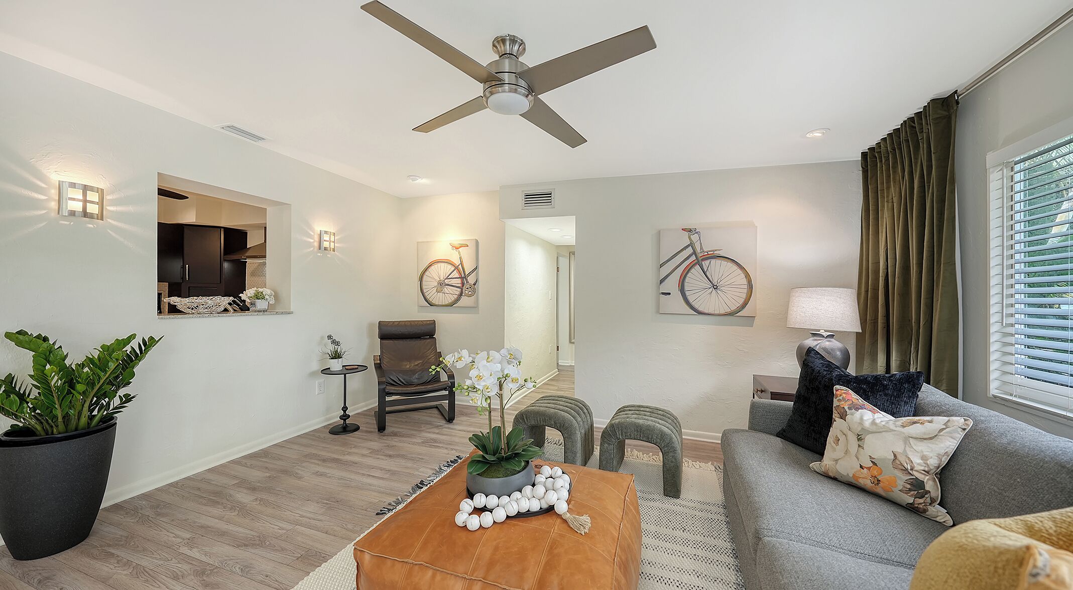 Un salon moderne doté d’un ventilateur de plafond, d’un canapé, d’une table basse et d’un coin repas avec une table et des chaises.