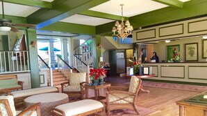 A spacious living area with a staircase, wicker furniture, and a chandelier. - Direct Ocean Front, Top Floor Studio Paradise (Kapaa)