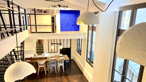 A modern interior with a dining area, staircase, and large windows. - TOP LOCATION, TOP CENTER , POMPIDOU/MARAIS/LOUVRE (Paris)