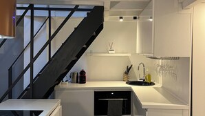 A compact kitchen with white cabinets, a dishwasher, a sink with a wine rack, and a black staircase. - TOP LOCATION, TOP CENTER , POMPIDOU/MARAIS/LOUVRE (Paris)