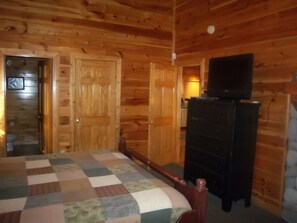 A wooden cabin interior with a bed, dresser, and television. - Romantic Luxury Getaway,Breathtaking View,Free HS WiFi,Htub,Xm,Smart Home Theatr (Pigeon Forge)