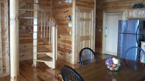 Un interior de madera con una mesa de comedor, sillas, un refrigerador y una escalera.