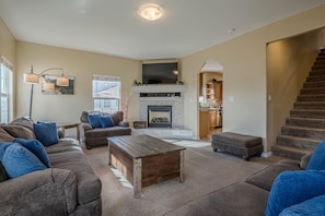 A spacious living room with a fireplace, a large flat-screen TV mounted above it, and a cozy seating area with sofas and a coffee table. - Juniper I: Fire Pit, Grill, and Bikes (Fruita)