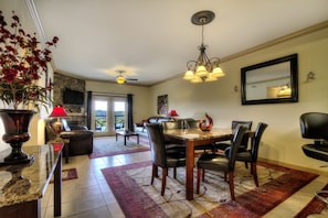 A dining area with a table, chairs, and a chandelier. There is a fireplace and a television in the background. - John's Mtn Blessing  w/ 2 Pools, Hot tub, Arcade Games 7 BR & 6 BA.  Sleeps 20+ (Pigeon Forge)