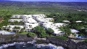 Un resort con varias edificaciones, una piscina y vistas al océano y al paisaje circundante.
