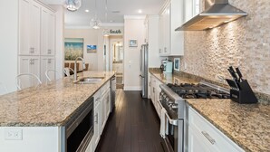Una cocina moderna con encimeras de granito, electrodomésticos de acero inoxidable y armarios blancos.