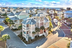 A coastal residential area with multi-story houses, a paved road, and a truck parked on the street.