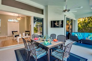 A dining area with a table set for six, surrounded by chairs with patterned cushions.