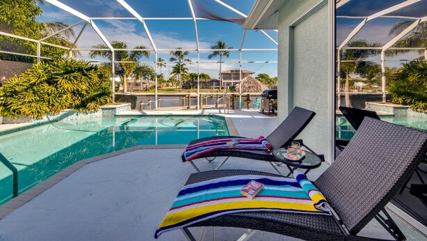 Un área de piscina con sillones de descanso y un porche cubierto.