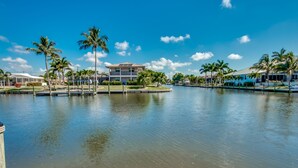 Una propiedad frente al mar con piscina, palmeras y un edificio grande de techo blanco.