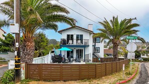 A two-story house with a balcony, a covered patio area, and a fenced backyard.