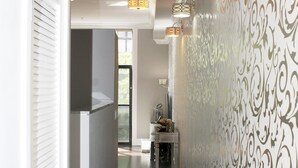 A hallway with patterned wallpaper, a modern kitchen area, and a dining space with a table and chairs. - Luxury Condo in Santana Row - Silicon Valley - Levi's Stadium (San Jose)