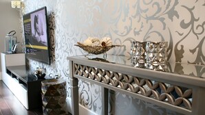A modern living room with a TV, decorative wall, and a console table with a decorative bowl and candle holders. - Luxury Condo in Santana Row - Silicon Valley - Levi's Stadium (San Jose)