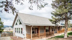 A lodge with a covered porch, a small deck, and a view of the mountains.