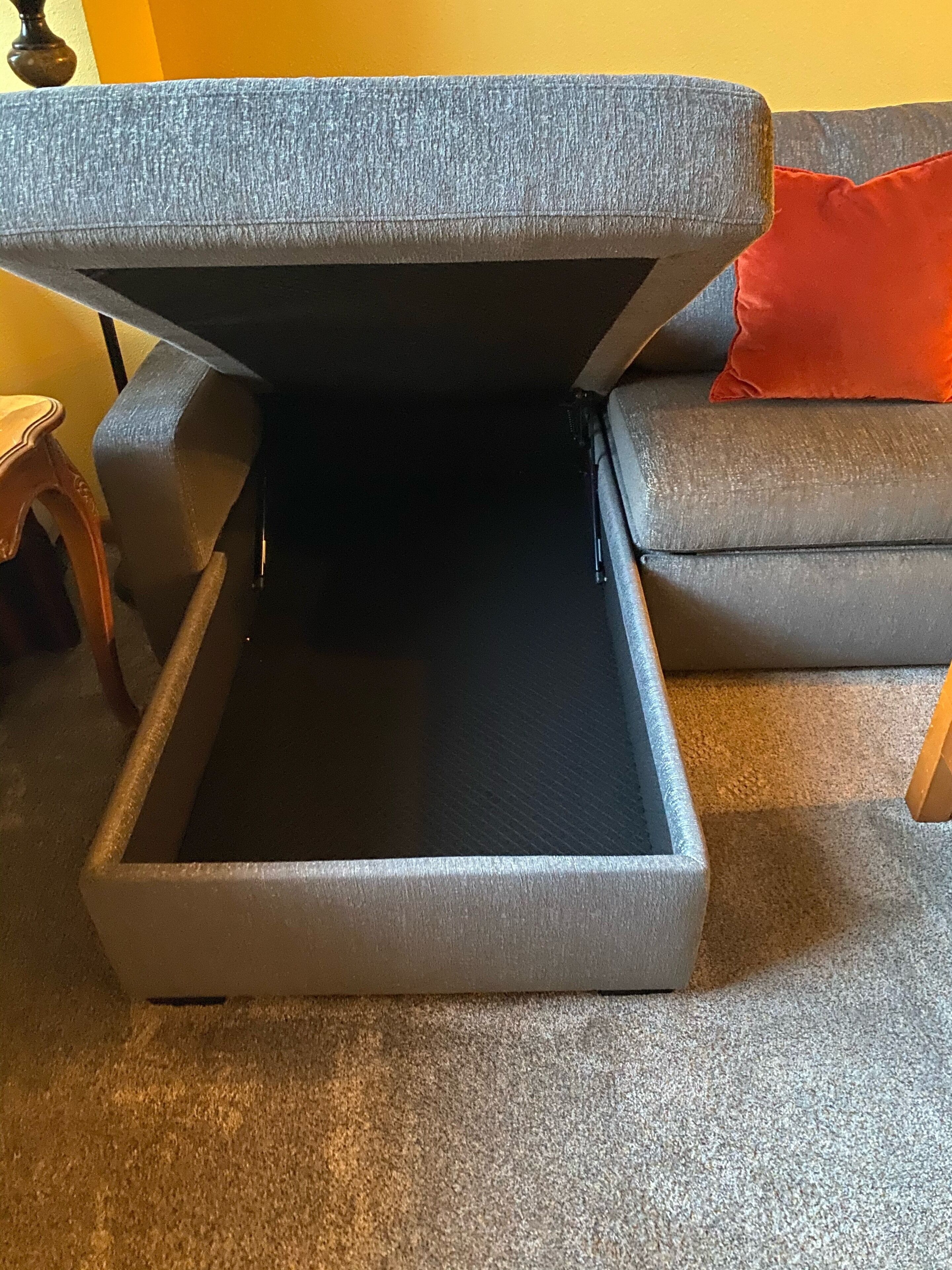 A gray sofa with a built-in storage compartment.