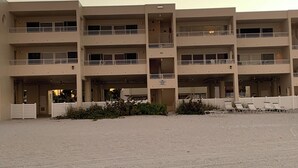 A multi-story building with balconies and a sandy ground area. - Gulf side! No crossing the street to get to the beach! COQUINA BEACH CLUB 109 (Bradenton Beach)
